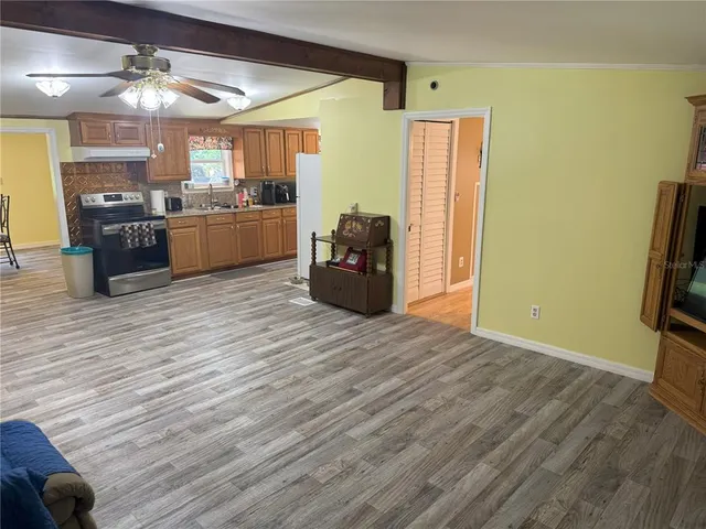 a living room with stainless steel appliances kitchen island granite countertop a refrigerator a stove top oven a sink and dishwasher