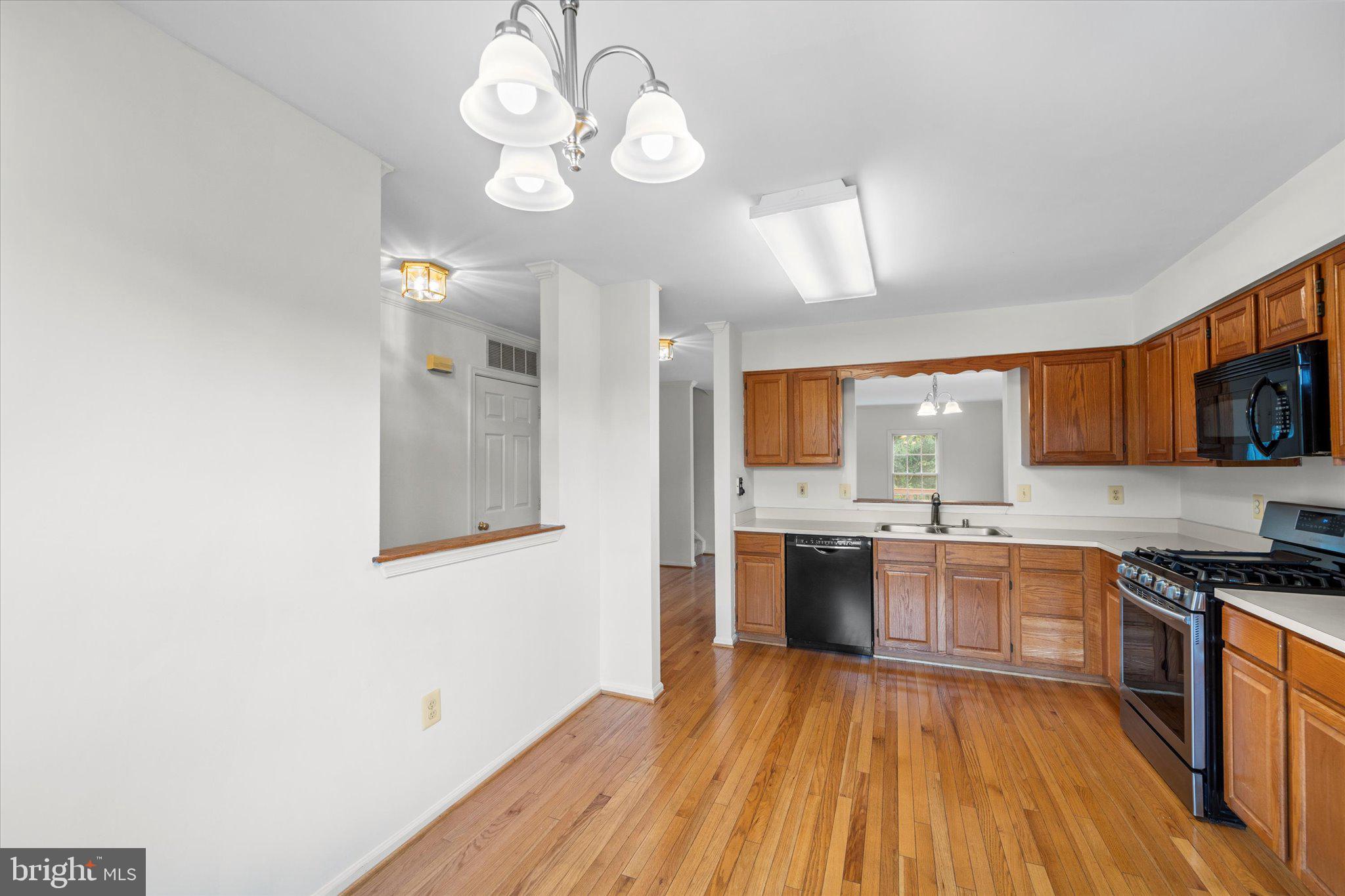 7849 Sabre Court Manassas, VA 20109 - Photo 7 of 35 a large kitchen with a wooden floor and stainless steel appliances