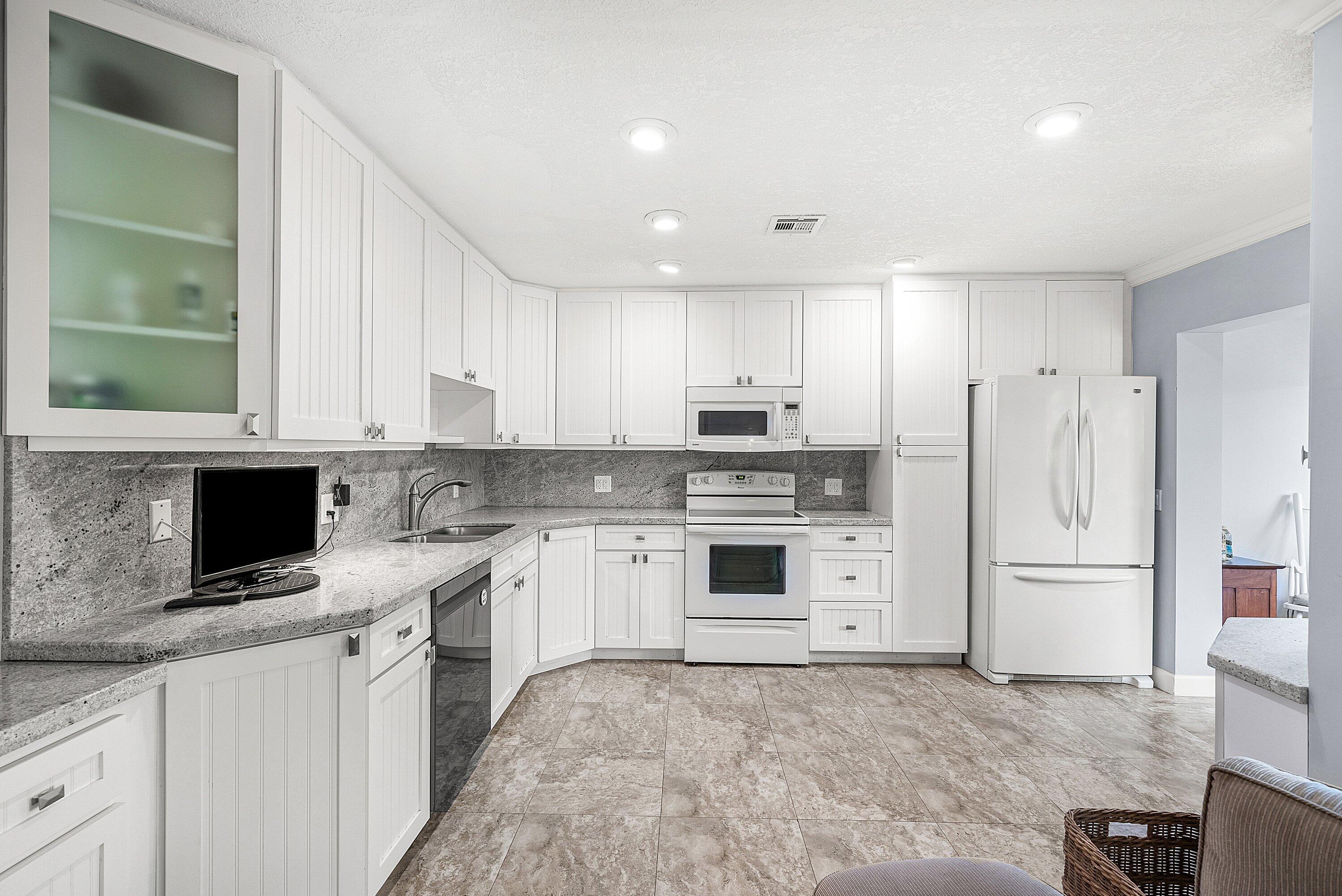 11212 Quail Covey Road, Unit GREEN HERON N Boynton Beach, FL 33436 - Photo 2 of 55 a kitchen with white cabinets and white appliances