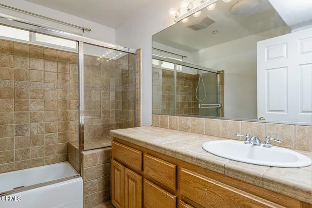 a bathroom with a sink and mirror with bathtub