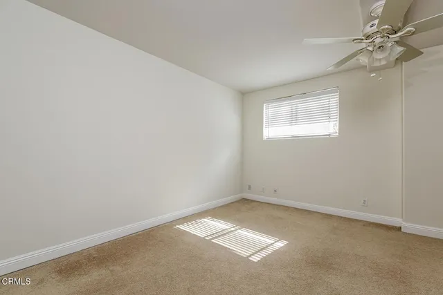an empty room with a fan & a window