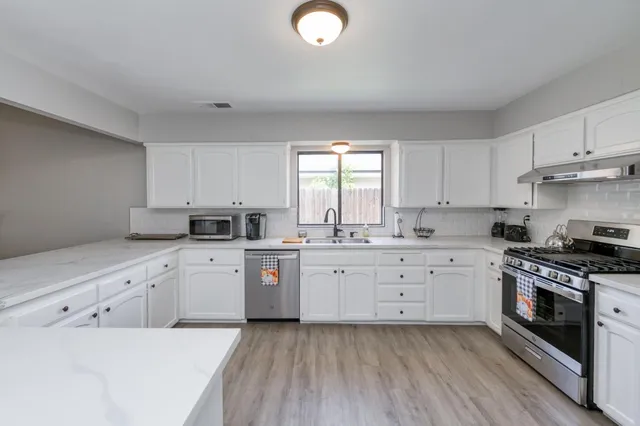 a kitchen with cabinets stainless steel appliances a sink and a window