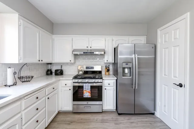 a kitchen with white cabinets and stainless steel appliances