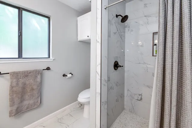 a bathroom with a granite countertop toilet a sink and shower
