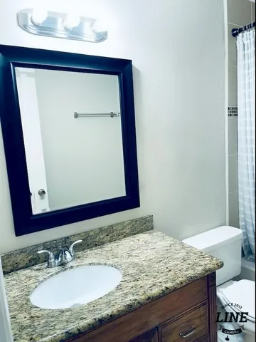 a bathroom with a granite countertop bathtub sink vanity mirror and toilet