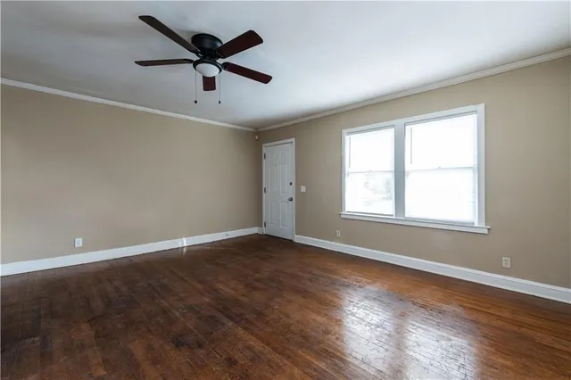 an empty room with wooden floor fan and windows
