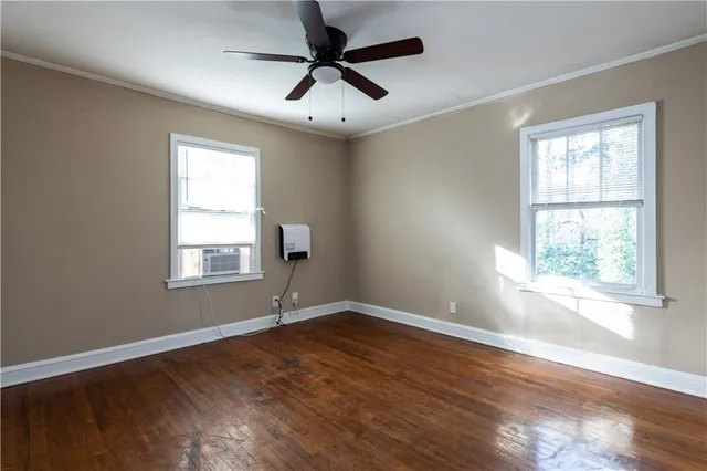 a view of an empty room with wooden floor and a window