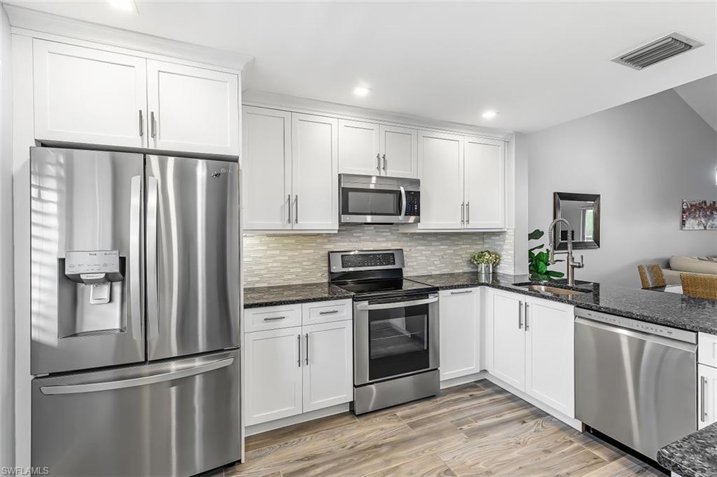 5695 Rattlesnake Hammock Road, Unit 202B Naples, FL 34113 - Photo 5 of 19 a kitchen with white cabinets and stainless steel appliances