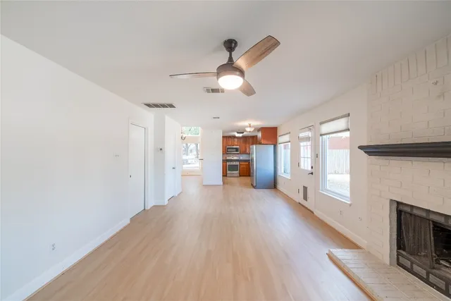 a view of a big room with wooden floor a fireplace and windows