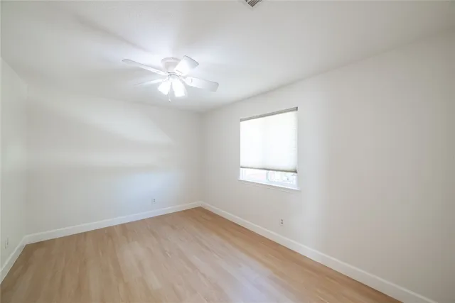 an empty room with a window and a fan