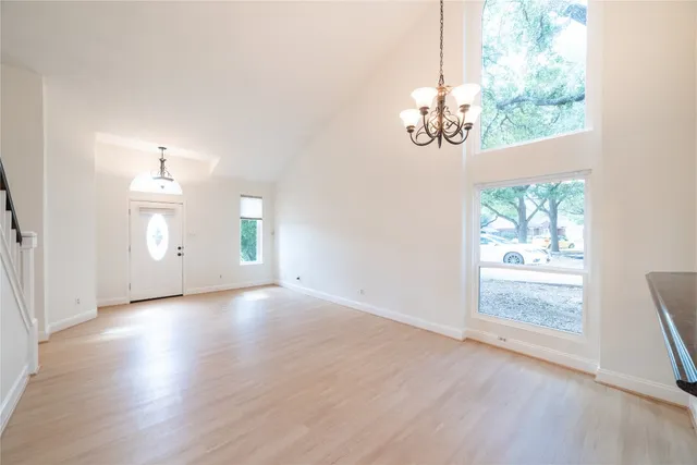 an empty room with wooden floor cabinet and windows