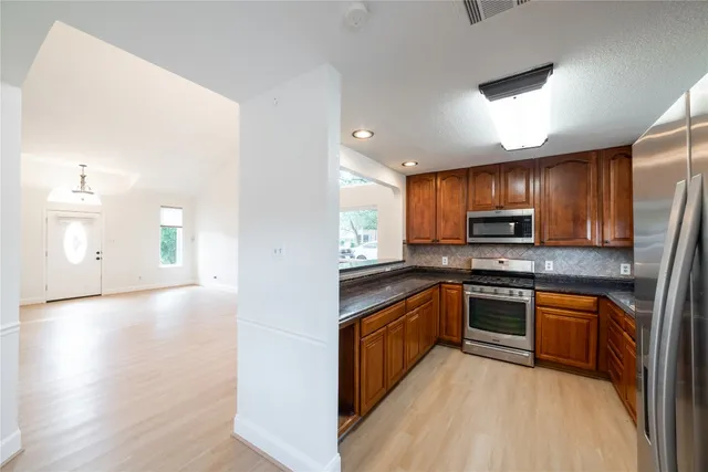 a kitchen with stainless steel appliances granite countertop a stove top oven a sink dishwasher a refrigerator and a microwave