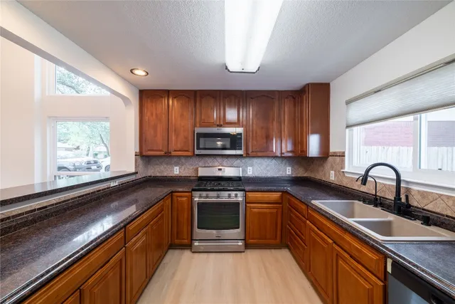 a kitchen with wooden cabinets a sink a window and stainless steel appliances