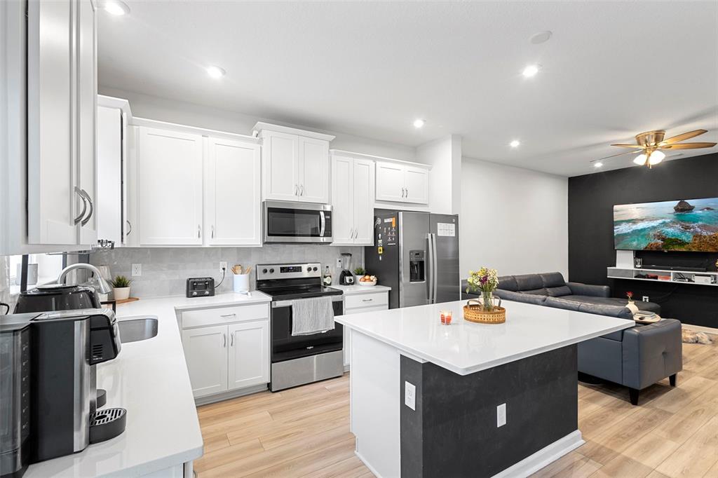 866 Spring Palms Loop Orlando, FL 32828 - Photo 5 of 26 a kitchen with stainless steel appliances a sink a stove top oven a counter space and cabinets