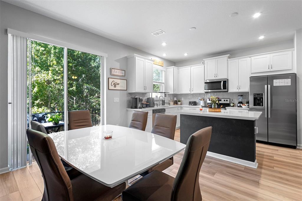 866 Spring Palms Loop Orlando, FL 32828 - Photo 7 of 26 a kitchen with a dining table chairs refrigerator and cabinets