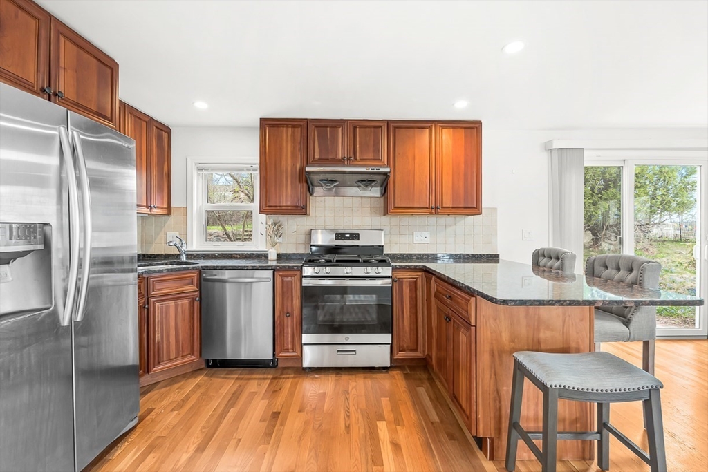 104 Wendell Street Winchester, MA 01890 - Photo 14 of 42 a kitchen with granite countertop wooden floors stainless steel appliances and a window