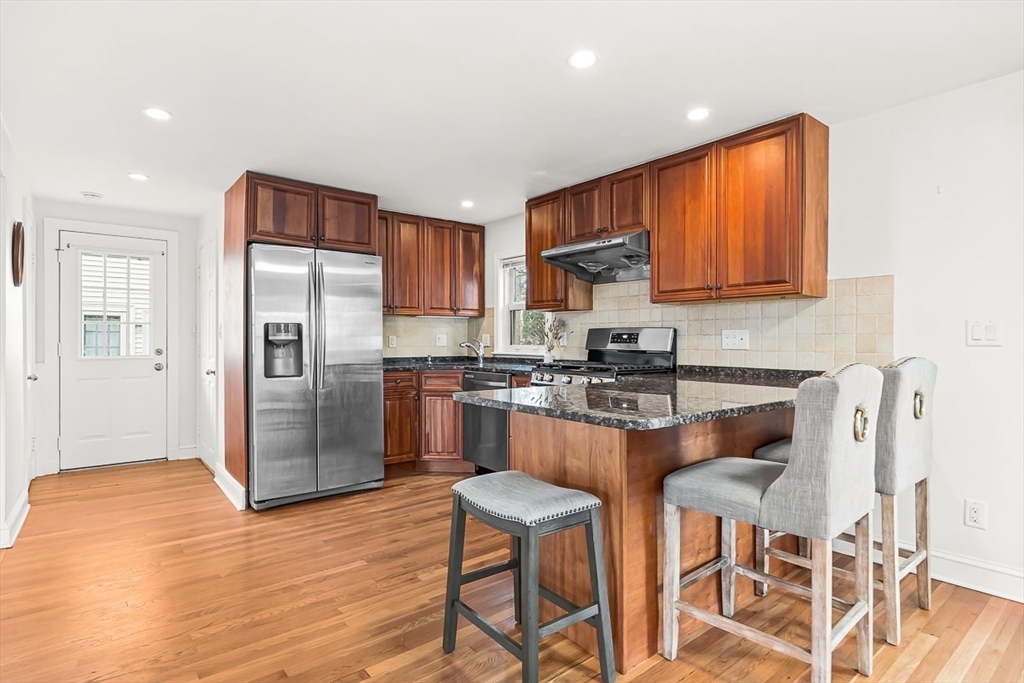 104 Wendell Street Winchester, MA 01890 - Photo 15 of 42 a kitchen with stainless steel appliances granite countertop a refrigerator a stove a sink dishwasher and a dining table with wooden floor