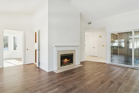an empty room with wooden floor fireplace and cabinet
