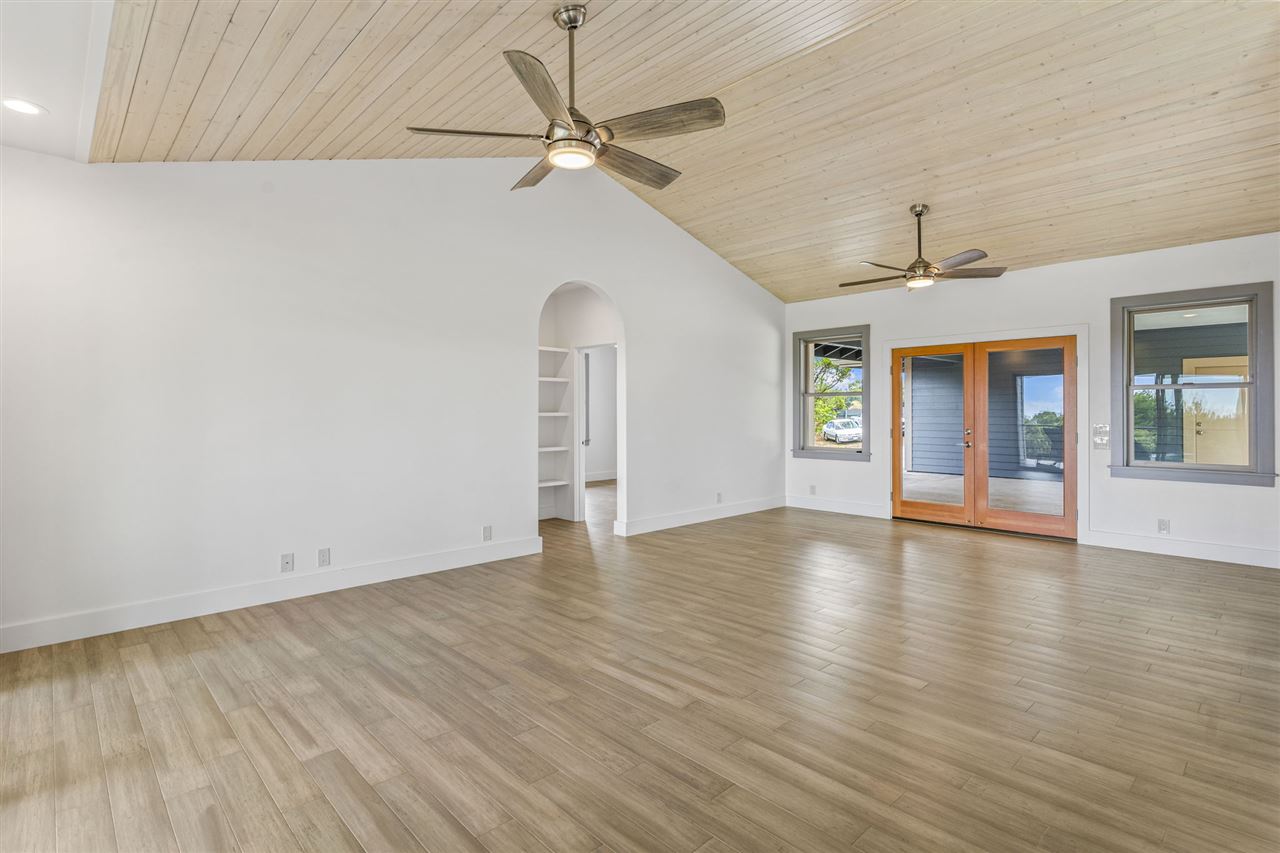 780 West Kuiaha Road Haiku, HI 96708 - Photo 22 of 30 an empty room with wooden floor chandelier fan and windows