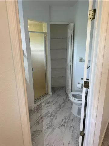 a bathroom with a granite countertop sink a toilet and shower