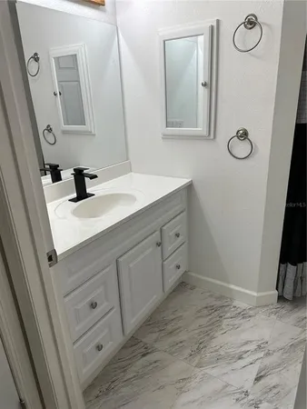 a en suite bathroom with a granite countertop sink and a mirror