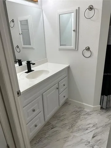 a en suite bathroom with a granite countertop sink and a mirror