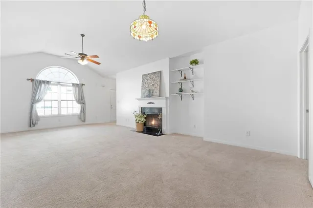 an empty room with a fireplace and chandelier fan