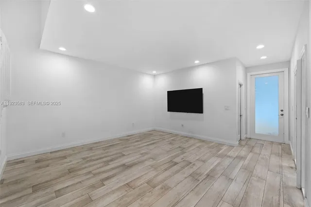 a view of an empty room with wooden floor and windows