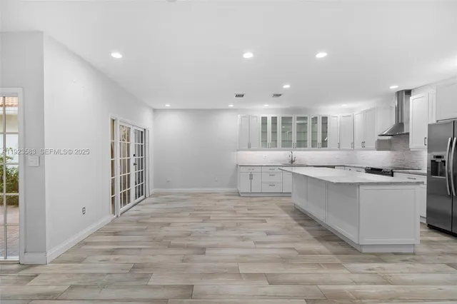 a large kitchen with stainless steel appliances kitchen island a large counter top and a stove top oven