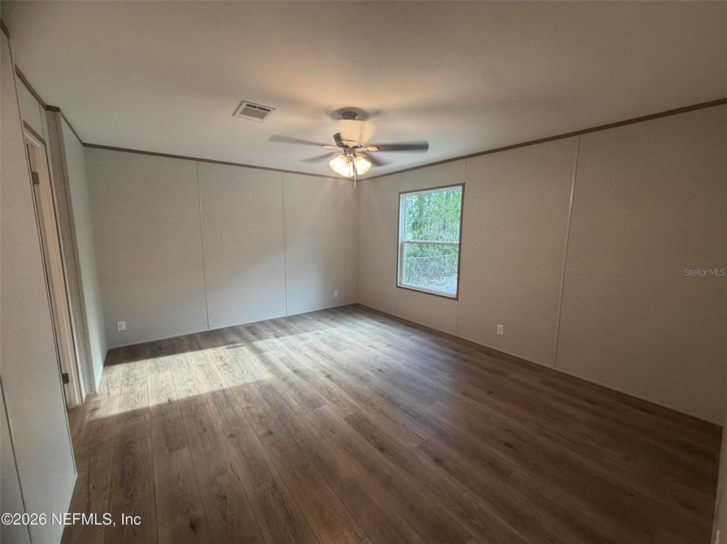 114 Nutmeg Trail Interlachen, FL 32148 - Photo 11 of 33 an empty room with wooden floor chandelier fan and windows