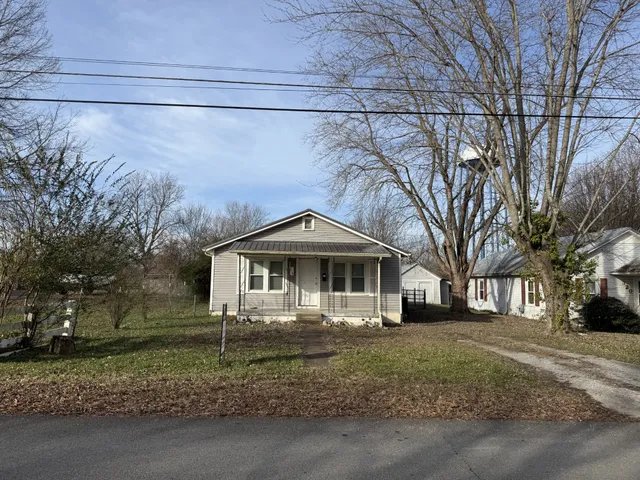 a front view of a house with a yard and large trees