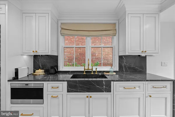 a kitchen with granite countertop a sink a stove and cabinets
