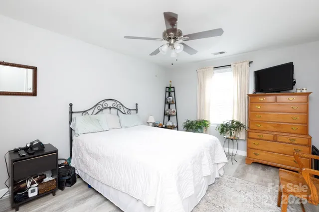a bedroom with a bed and a flat tv screen on dresser