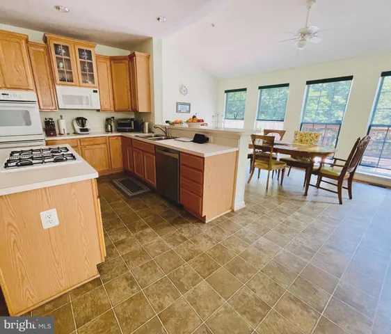a kitchen with a stove a sink a counter top space and living room