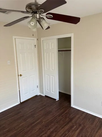 a view of an empty room with wooden floor ceiling fan and a window