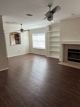an empty room with wooden floor ceiling fan and windows