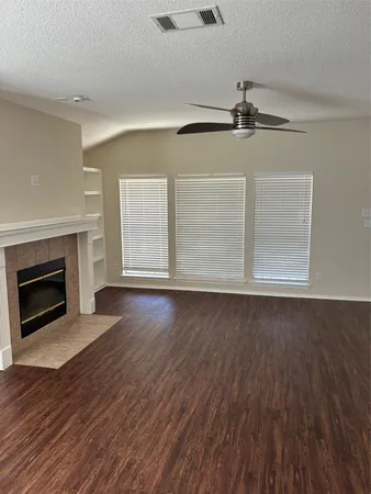 an empty room with wooden floor fireplace and windows
