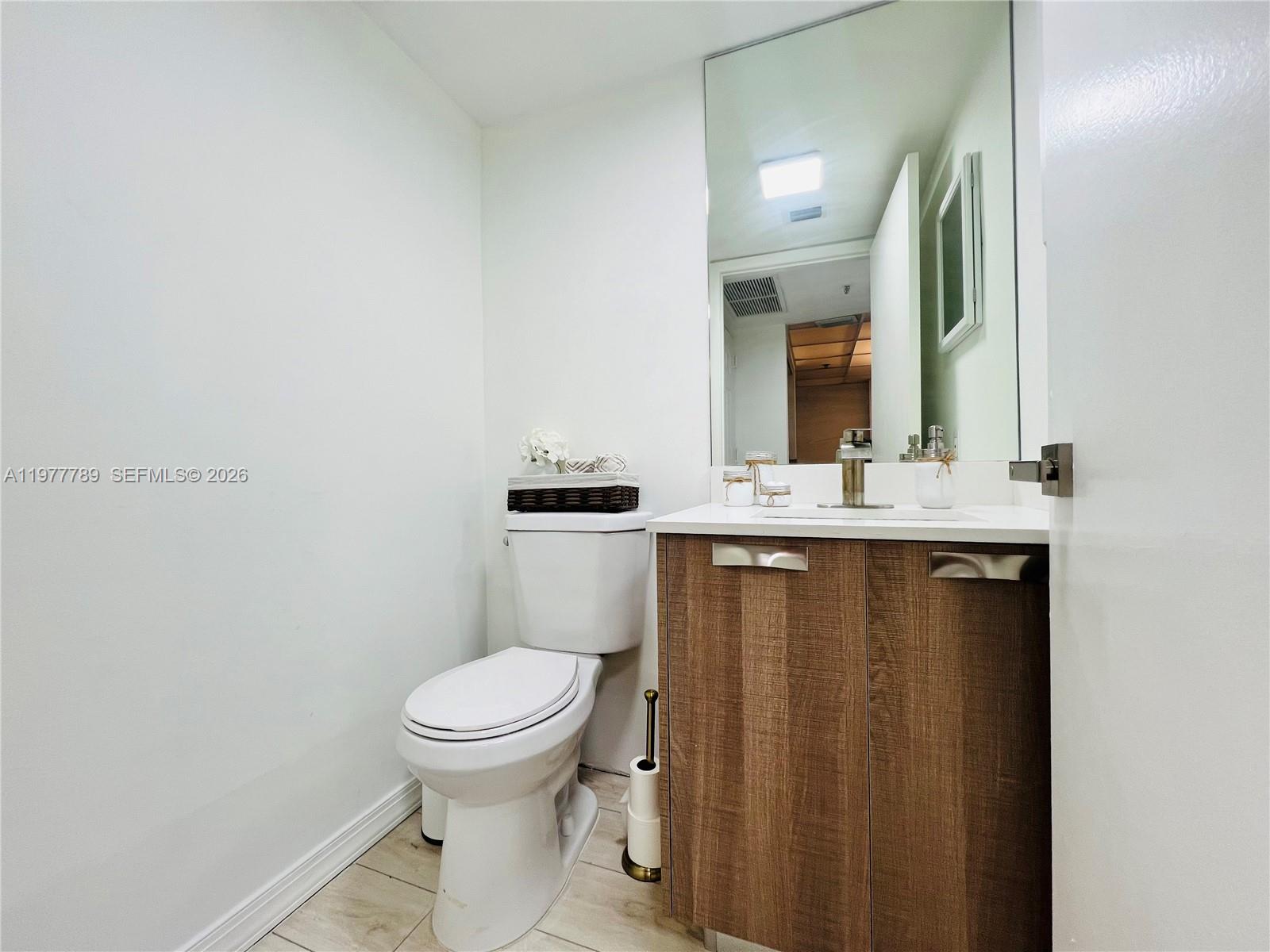 540 Brickell Key Drive, Unit 202 Miami, FL 33131 - Photo 16 of 25 a bathroom with a granite countertop sink toilet and mirror