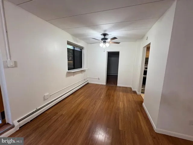 a view of an empty room with wooden floor and a window