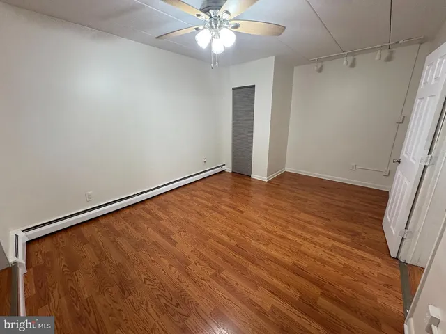 an empty room with wooden floor fan and windows