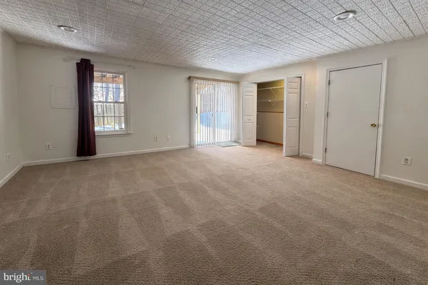 a view of an empty room with closet and a window
