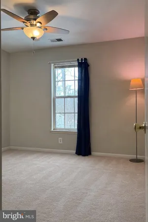 an empty room with a window and chandelier fan