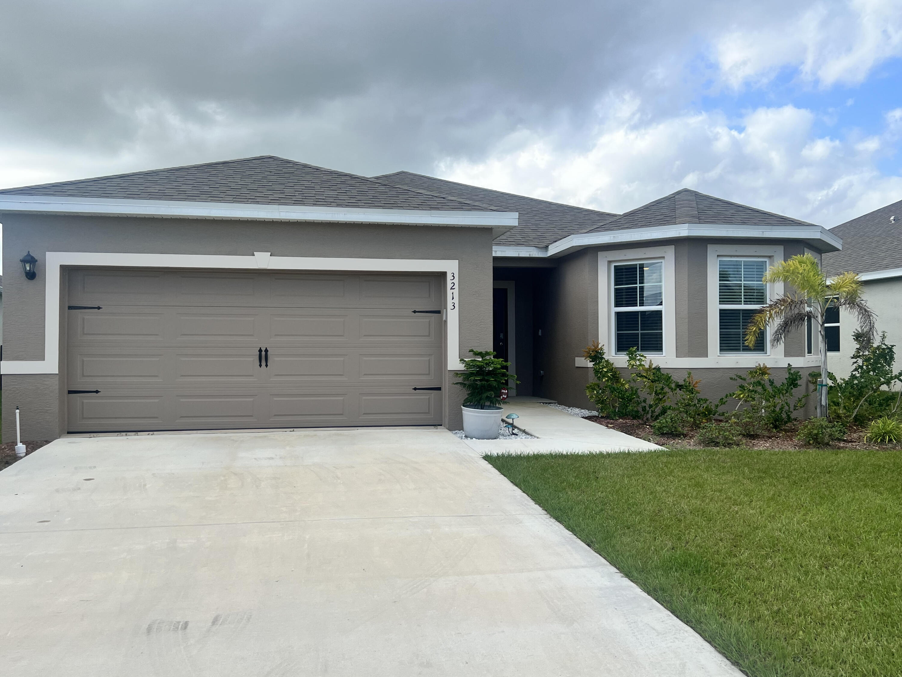 3213 Trinity Circle Fort Pierce, FL 34945 - Photo 1 of 20 a front view of a house with a yard and garage