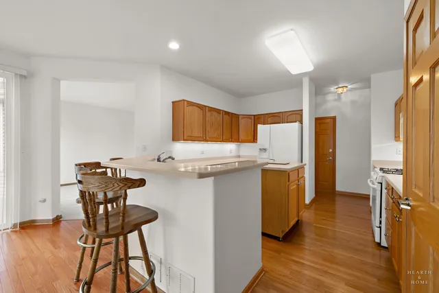 a kitchen with stainless steel appliances wooden floor and a refrigerator
