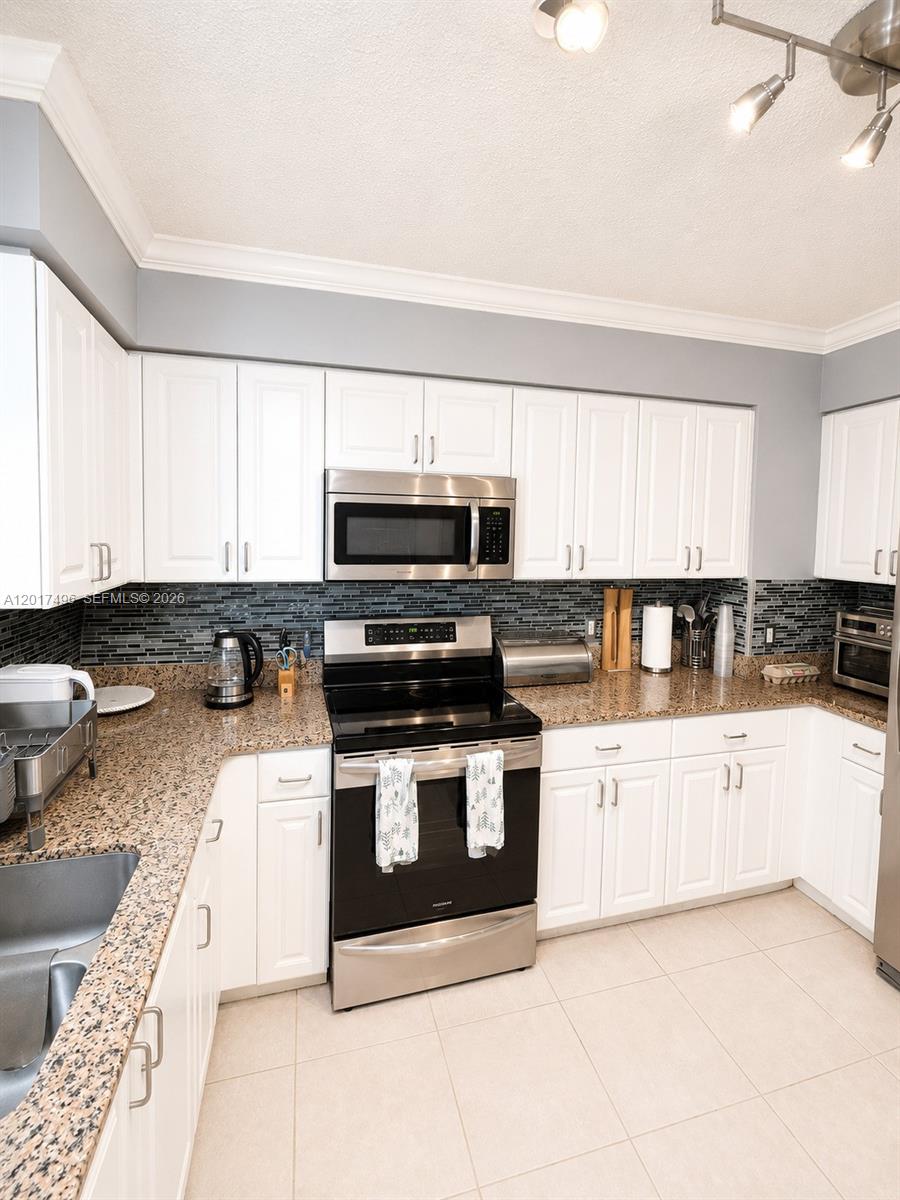 Brickell Miami, FL 33131 - Photo 6 of 19 a kitchen with stainless steel appliances granite countertop a stove a sink and a microwave