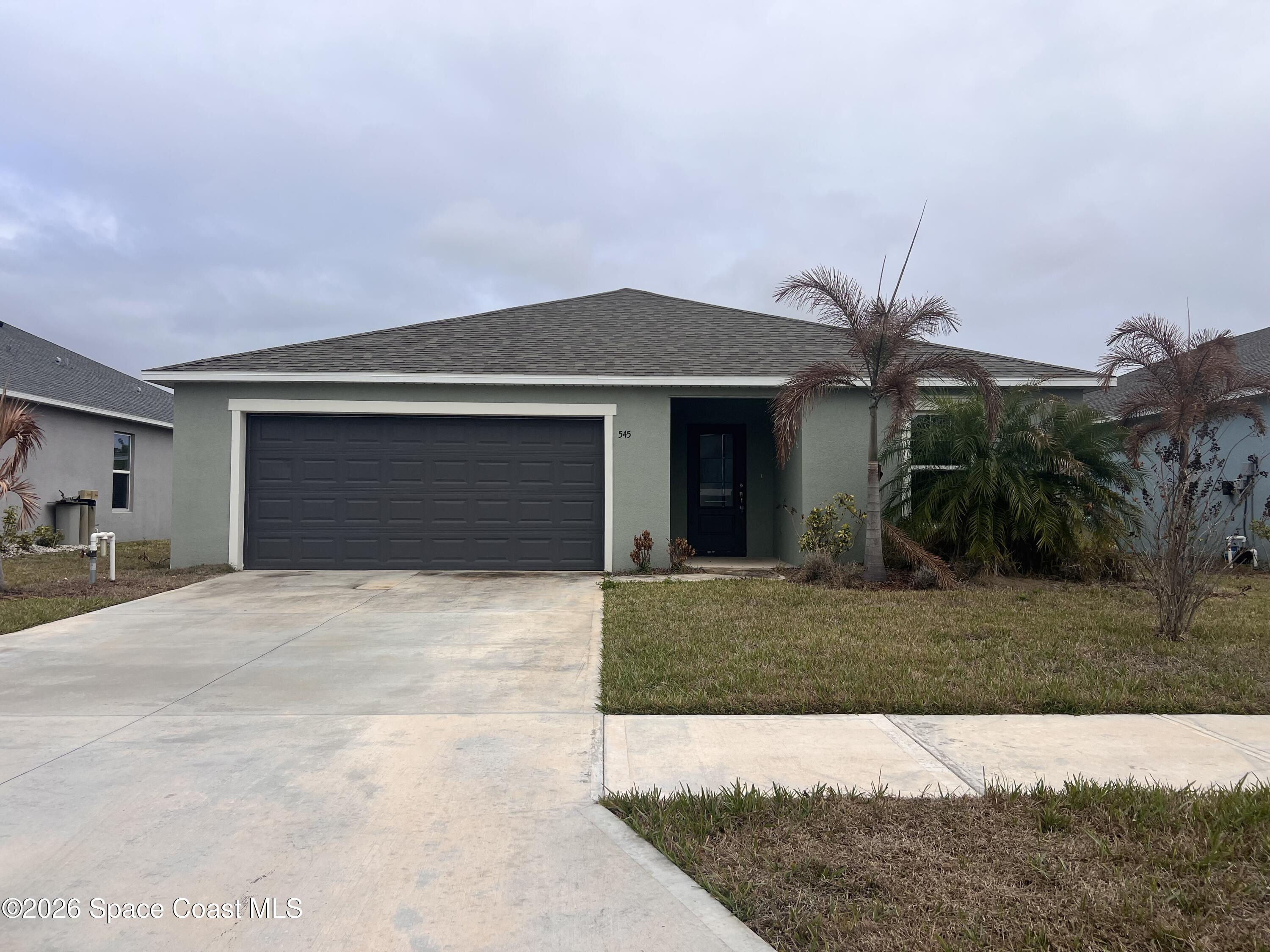 545 Cooper Court Palm Bay, FL 32908 - Photo 1 of 19 a front view of a house with a yard and garage