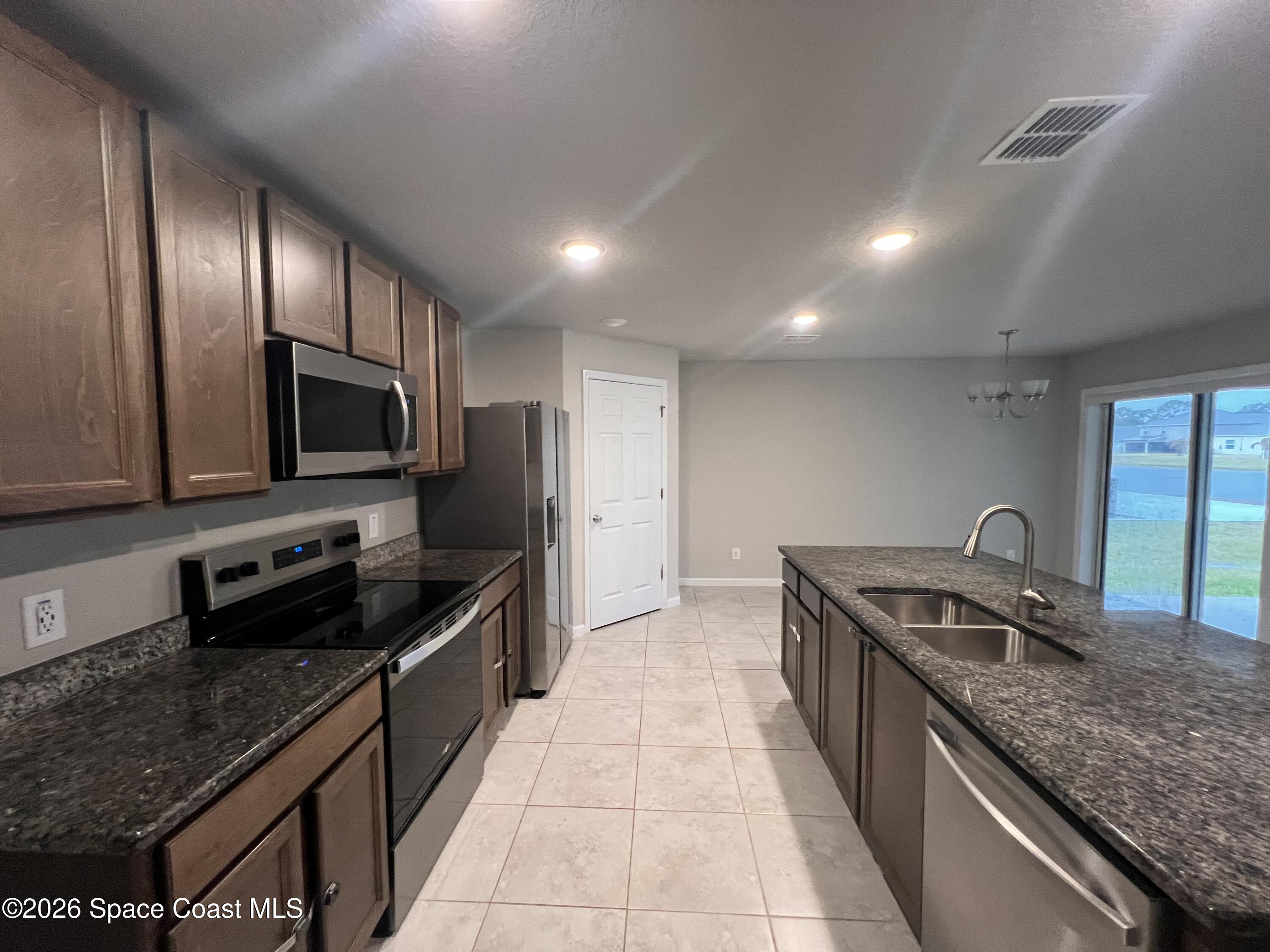 545 Cooper Court Palm Bay, FL 32908 - Photo 13 of 19 a kitchen with granite countertop stainless steel appliances a sink stove top oven and cabinets