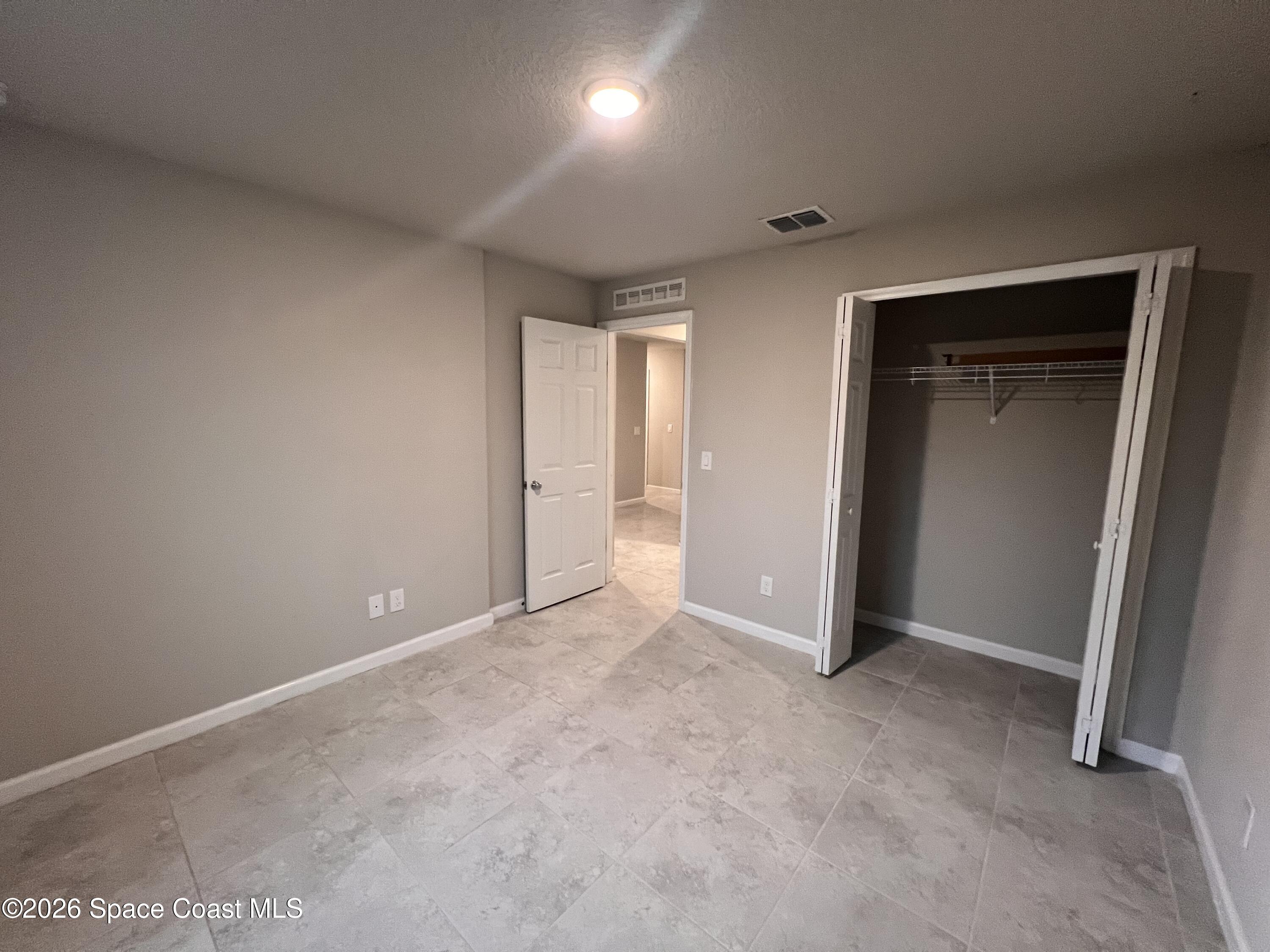 545 Cooper Court Palm Bay, FL 32908 - Photo 4 of 19 an empty room with closet and wooden door