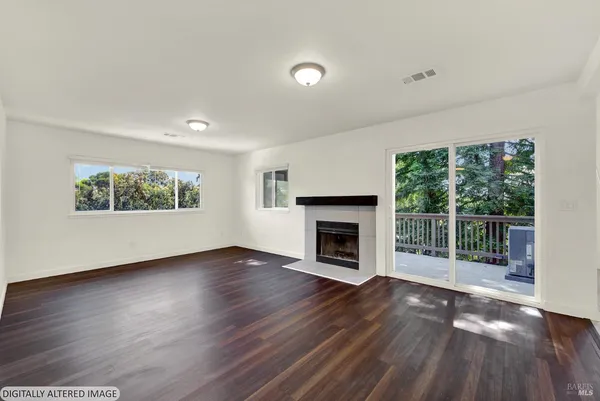 a view of empty room with wooden floor and kitchen