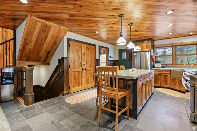 10205 East Moose Loop Road Salt Lake City, UT 84121 - Photo 12 of 50 Spacious kitchen featuring a central island with countertop seating, stainless steel appliances, abundant wood cabinetry, and large windows